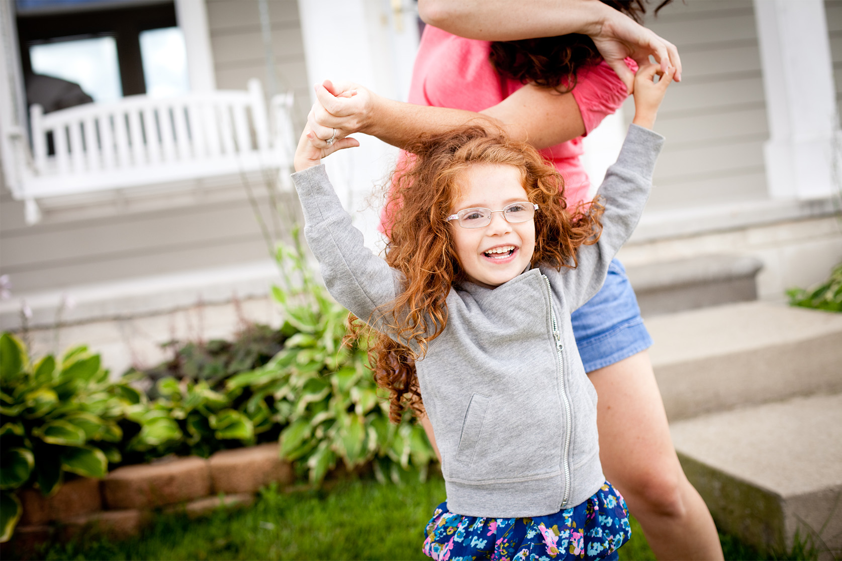 Young girl playing with her mom in the front yard